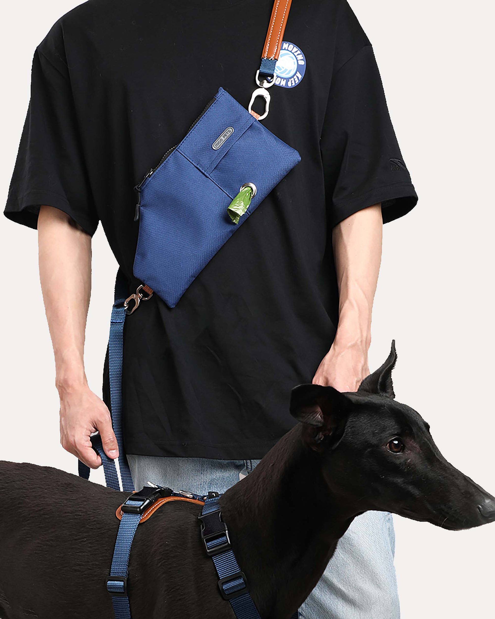 A person walking a dog while wearing a navy blue durable and versatile crossbody travel pouch.